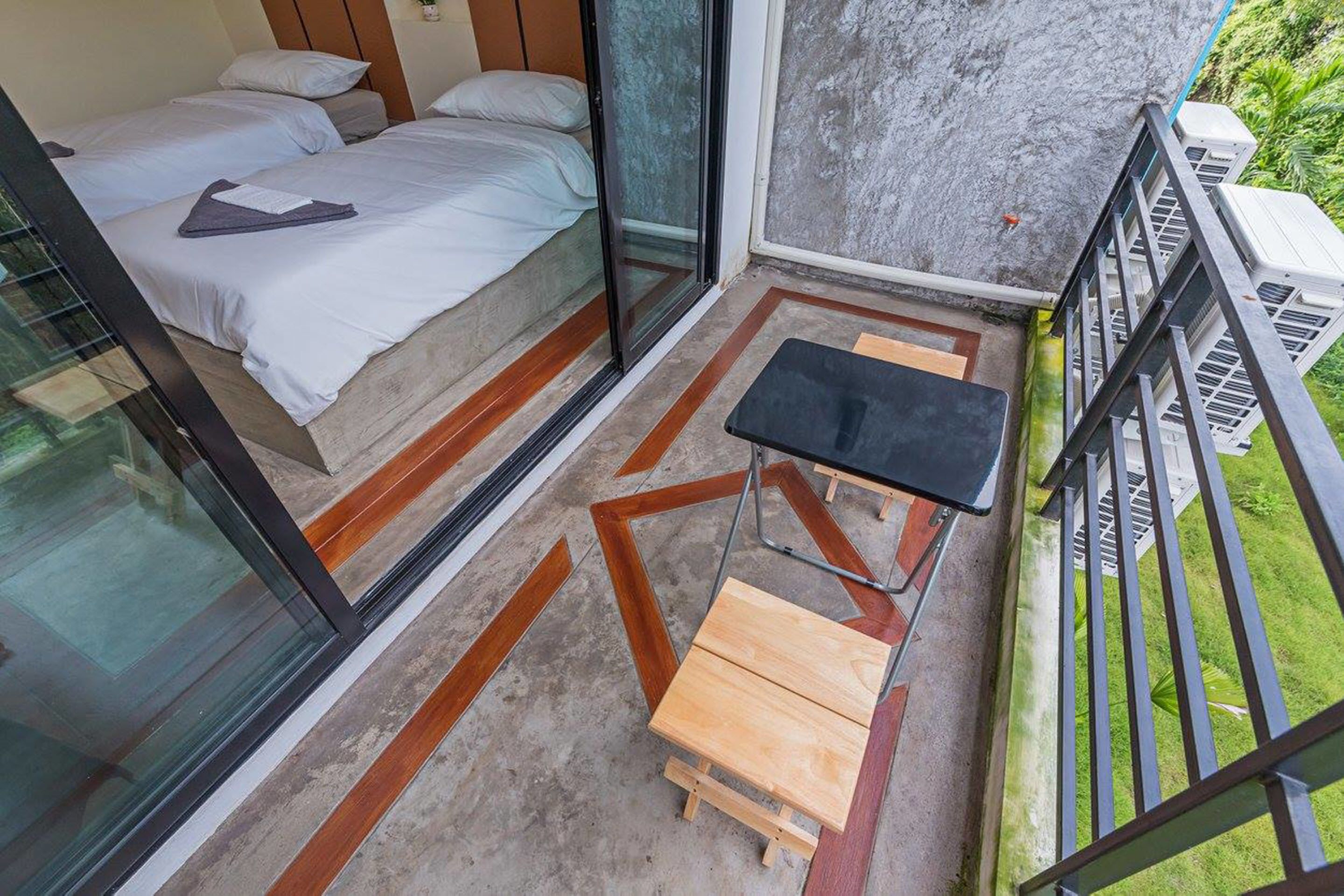 Ein Balkon mit einem Bett, einem kleinen Tisch und Blick auf Grünflächen.
