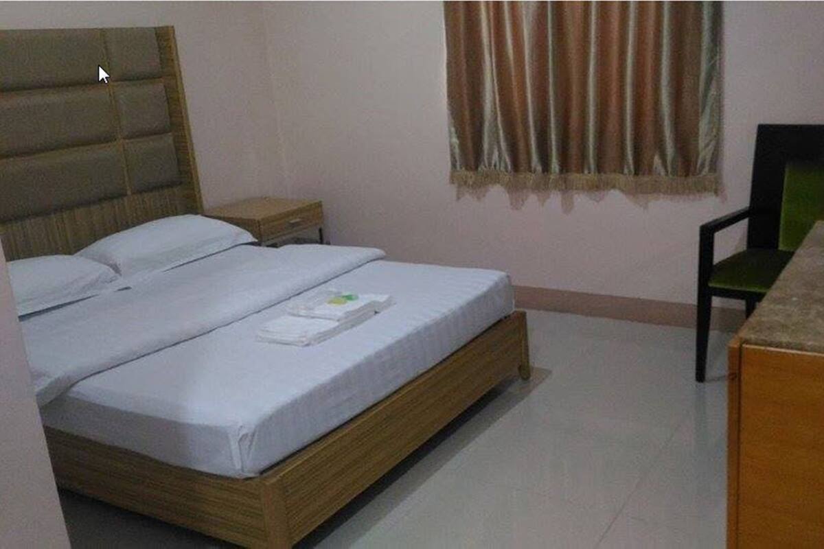 Een slaapkamer met een bed, nachtkastje, stoel en televisie.