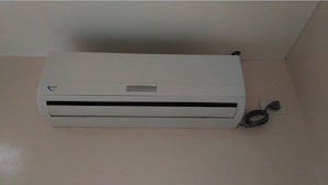 Eine weiße, tragbare Klimaanlage mit Bedienfeld und Stromkabel.