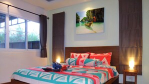A bedroom with a large bed, a painting of a boat on water, and a window with curtains. - Residence Harmonie (Rawai)