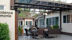 An outdoor seating area with wicker furniture and a covered section. - Residence Harmonie (Rawai)