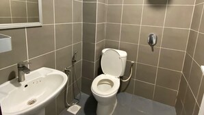 A small, modern bathroom with a toilet, sink, and shower. - The Garden Inn (Miri)