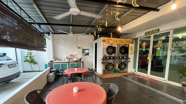 A cafe with outdoor seating, a tire repair station, and a car parked outside. - The Garden Inn (Miri)