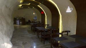 An interior with stone walls, wooden tables, and chairs arranged for dining. - Nandan Village Resort (Chandra)