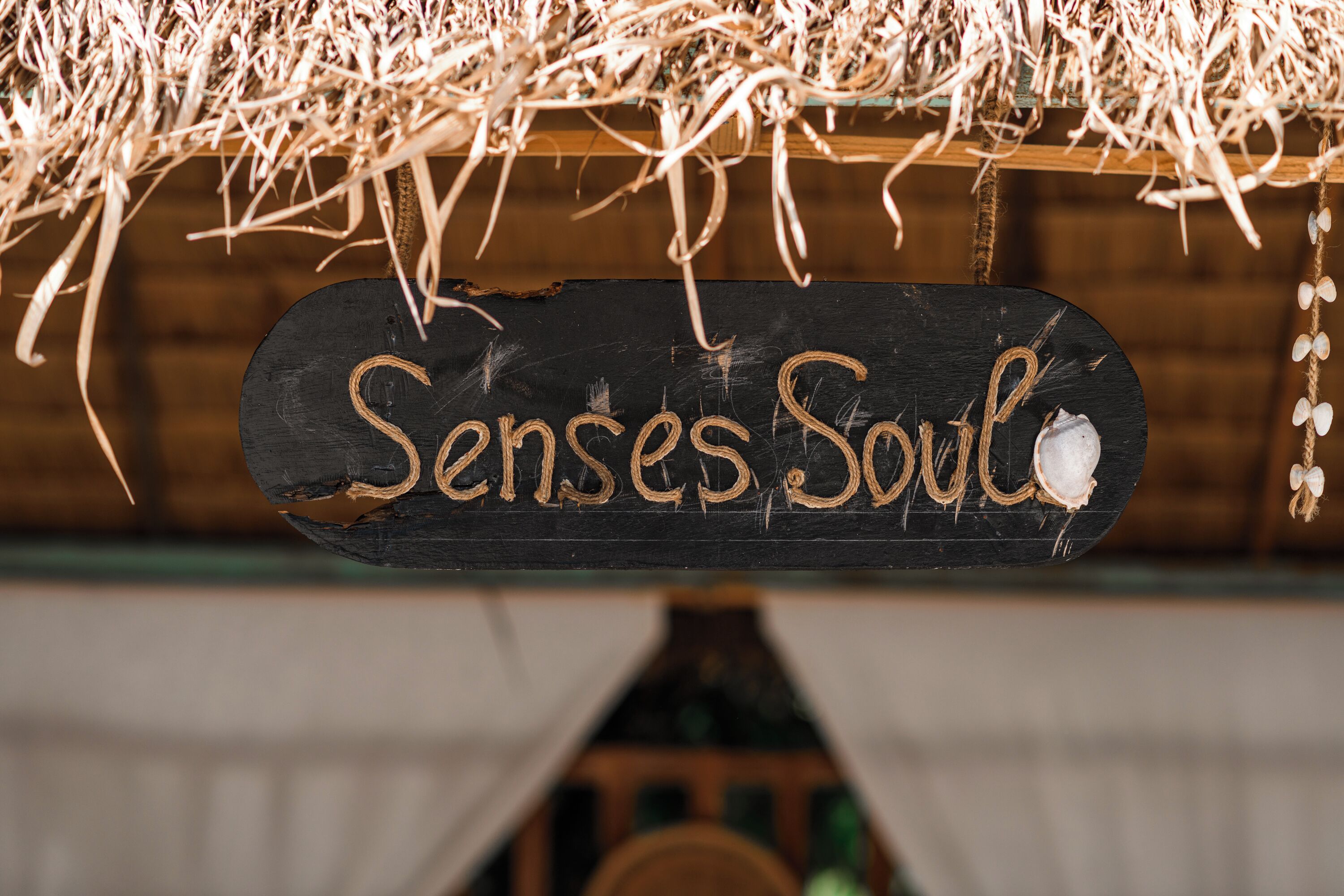 Un letrero de madera con el texto 'Senses Soul' colgado de una estructura rústica.