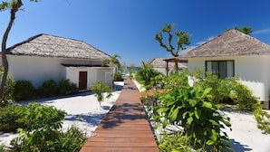 A pathway leading to beach huts with thatched roofs, surrounded by greenery and white sand. - The Royal Sands Koh Rong (Koh Rong)