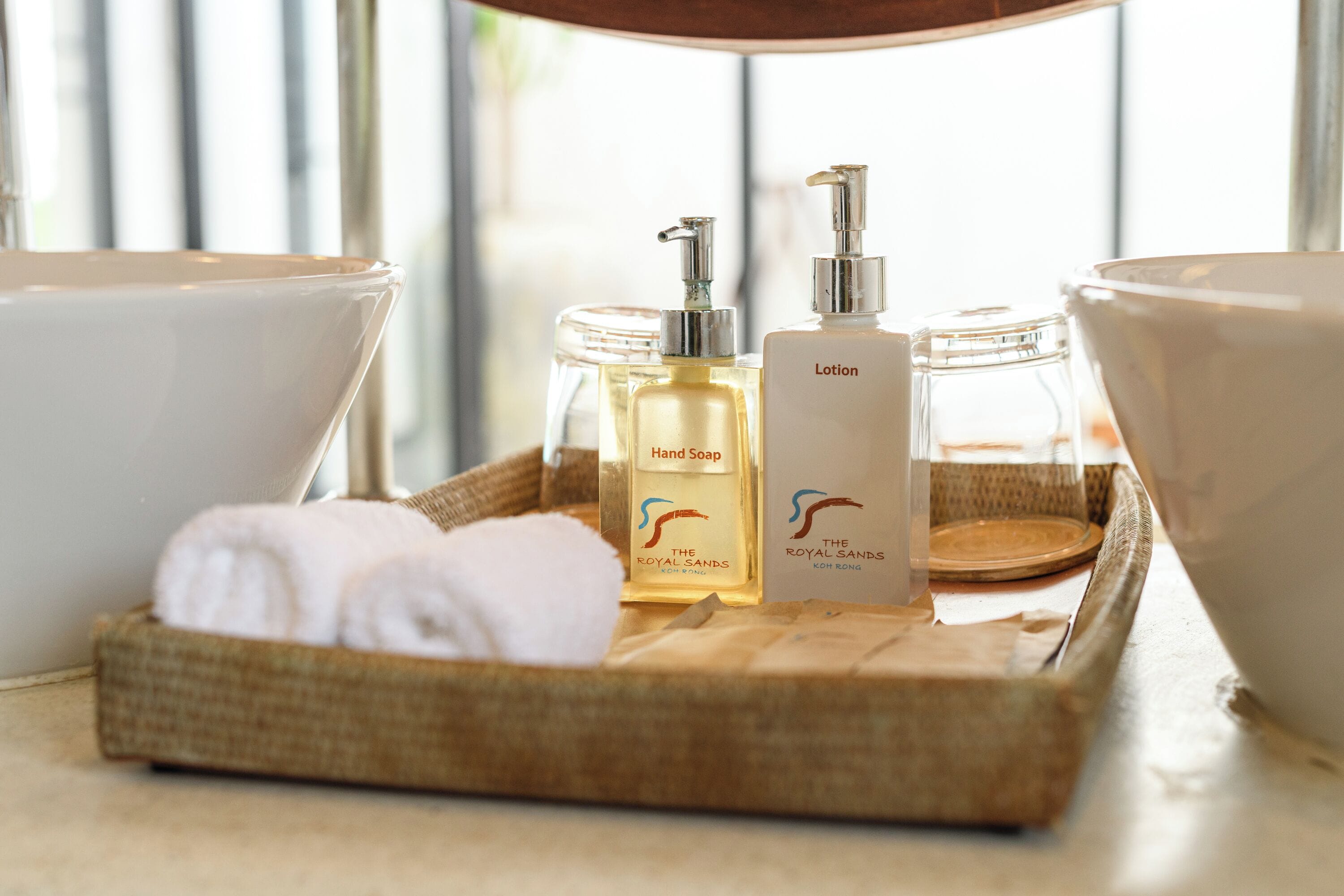 A bathroom vanity with a wicker tray holding toiletries, including hand soap and lotion.