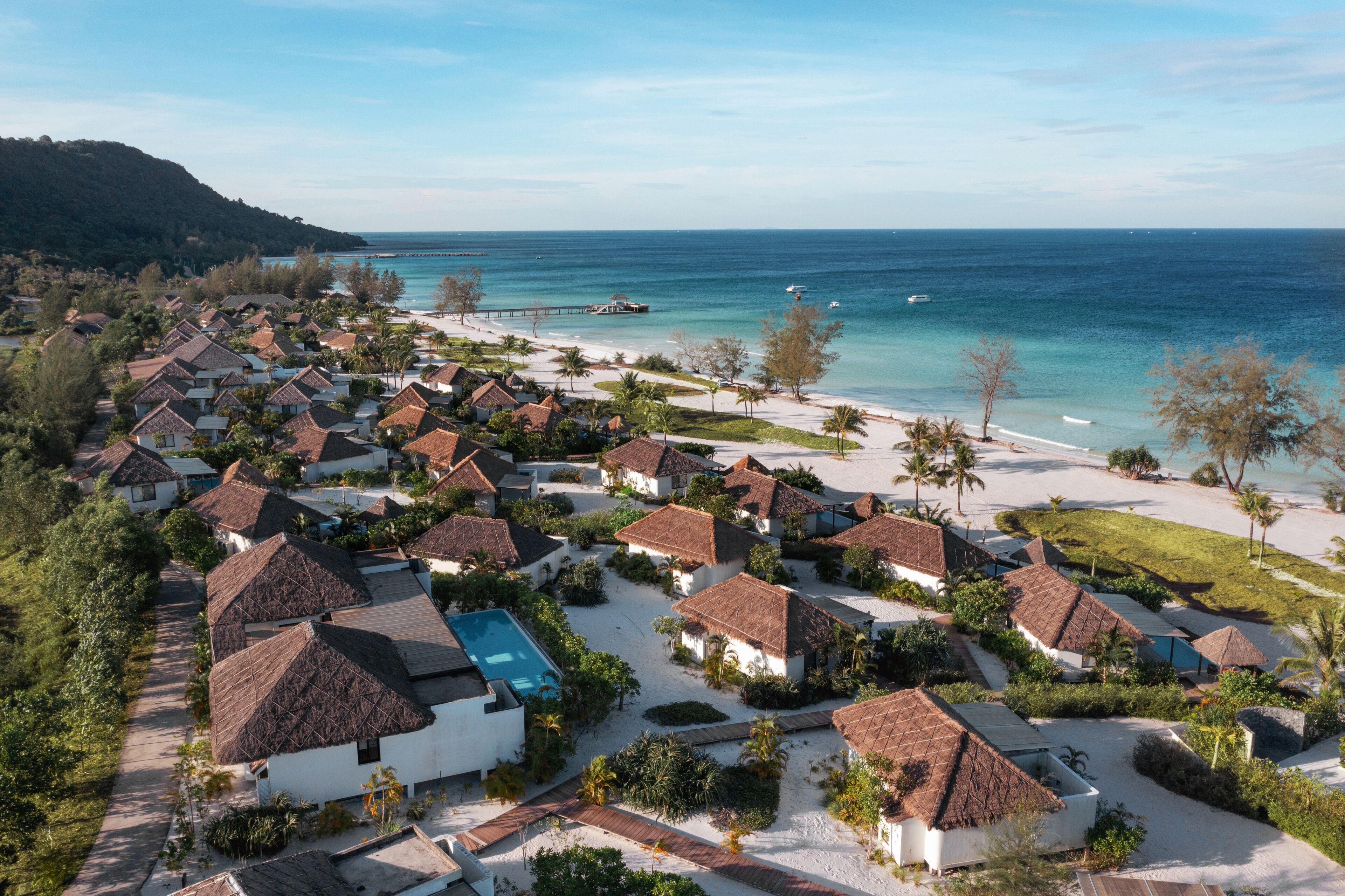 A resort with thatched-roof cottages, a swimming pool, and a beach.