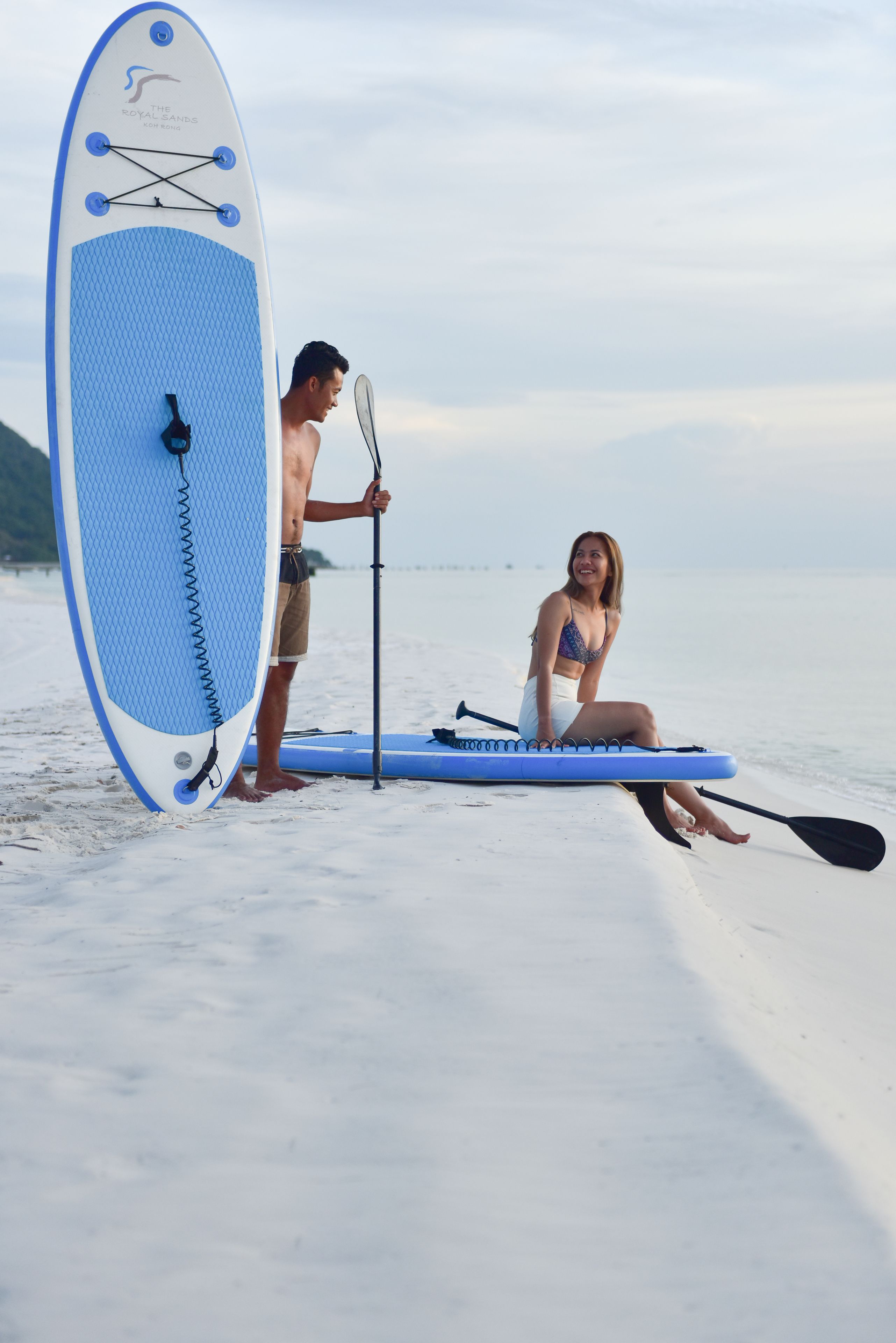 A beach scene with a paddleboard and a paddle.