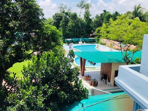 A resort with a large swimming pool surrounded by lush greenery and a covered outdoor seating area. - Tea Heaven Resort (Sreemangal)
