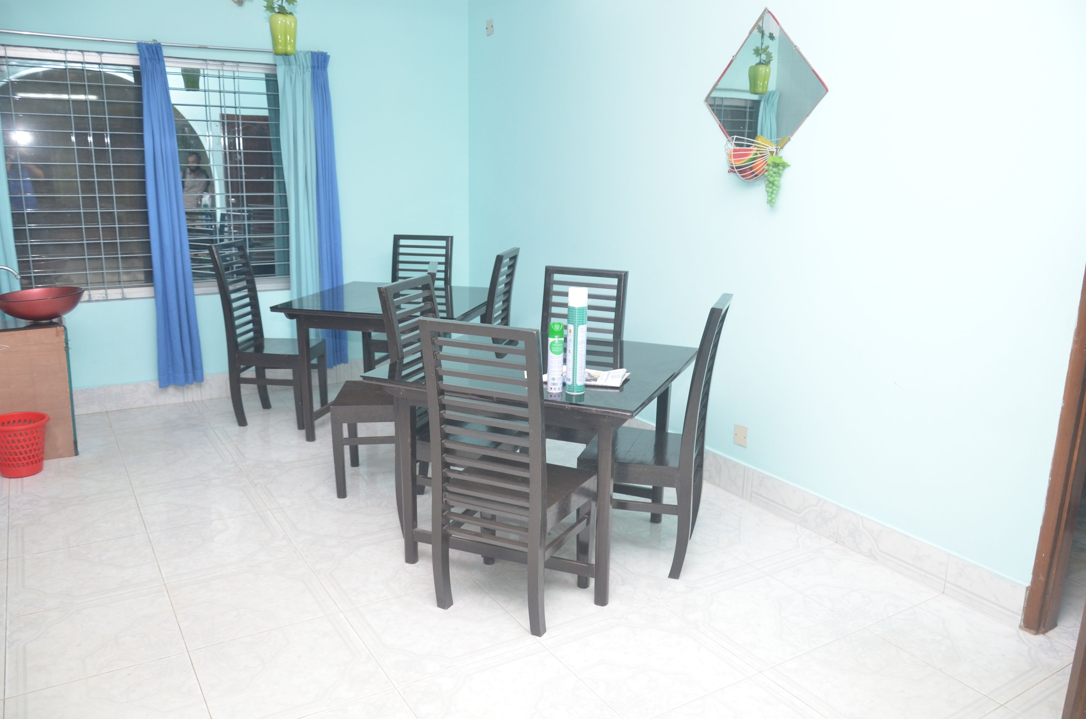 Un comedor con una mesa y sillas, una ventana con cortinas y una planta en maceta en la pared.