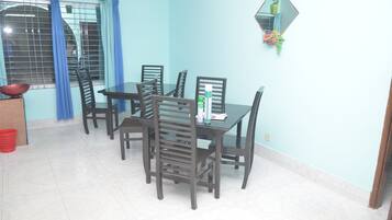 Un comedor con una mesa y sillas, una ventana con cortinas y una planta en maceta en la pared.