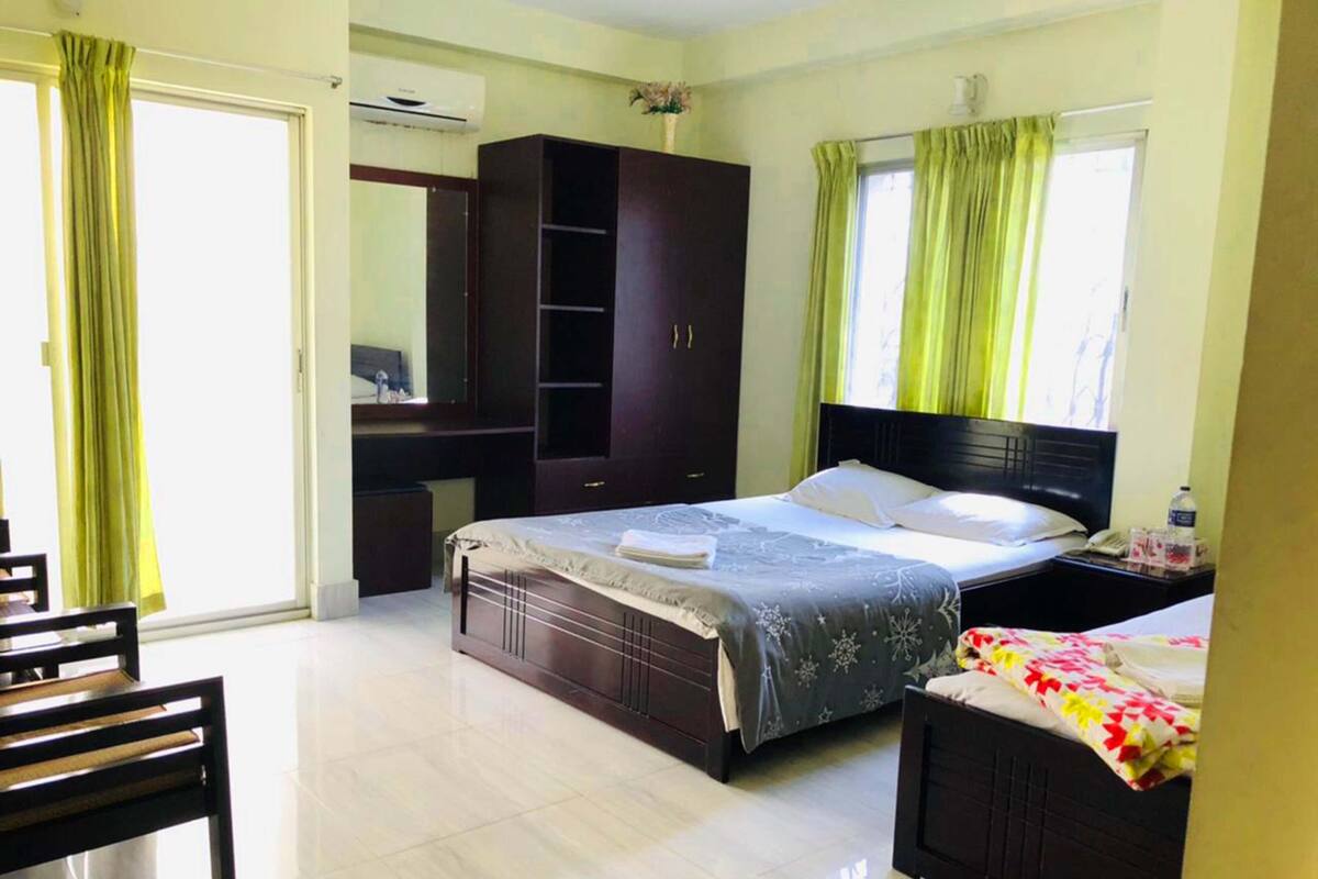 A bedroom with a bed, a desk, a chair, a wardrobe, and a window with curtains.