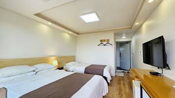 A hotel room with three beds, a TV, a desk, and a walk-in closet.