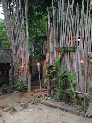 A rustic bamboo gate with a sign reading "Sustainable Earth & Nature."
