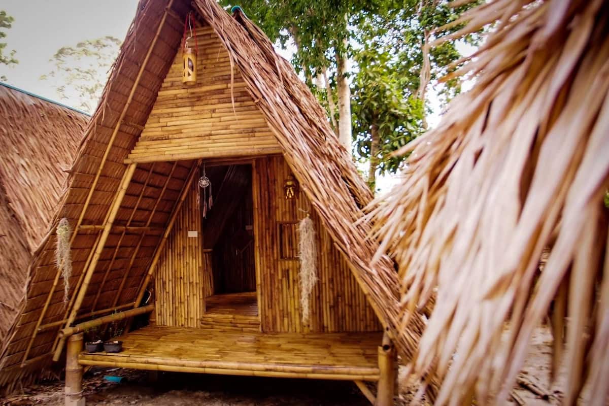 A thatched-roof hut with a wooden interior, a small porch, and a door.