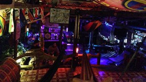 Uma área de bar com piso estampado, móveis de madeira e decorações penduradas.