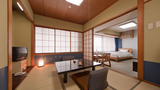A traditional Japanese-style room with tatami flooring, a low table, and a futon bed. - Subaruyado Yoshino (Tokushima)