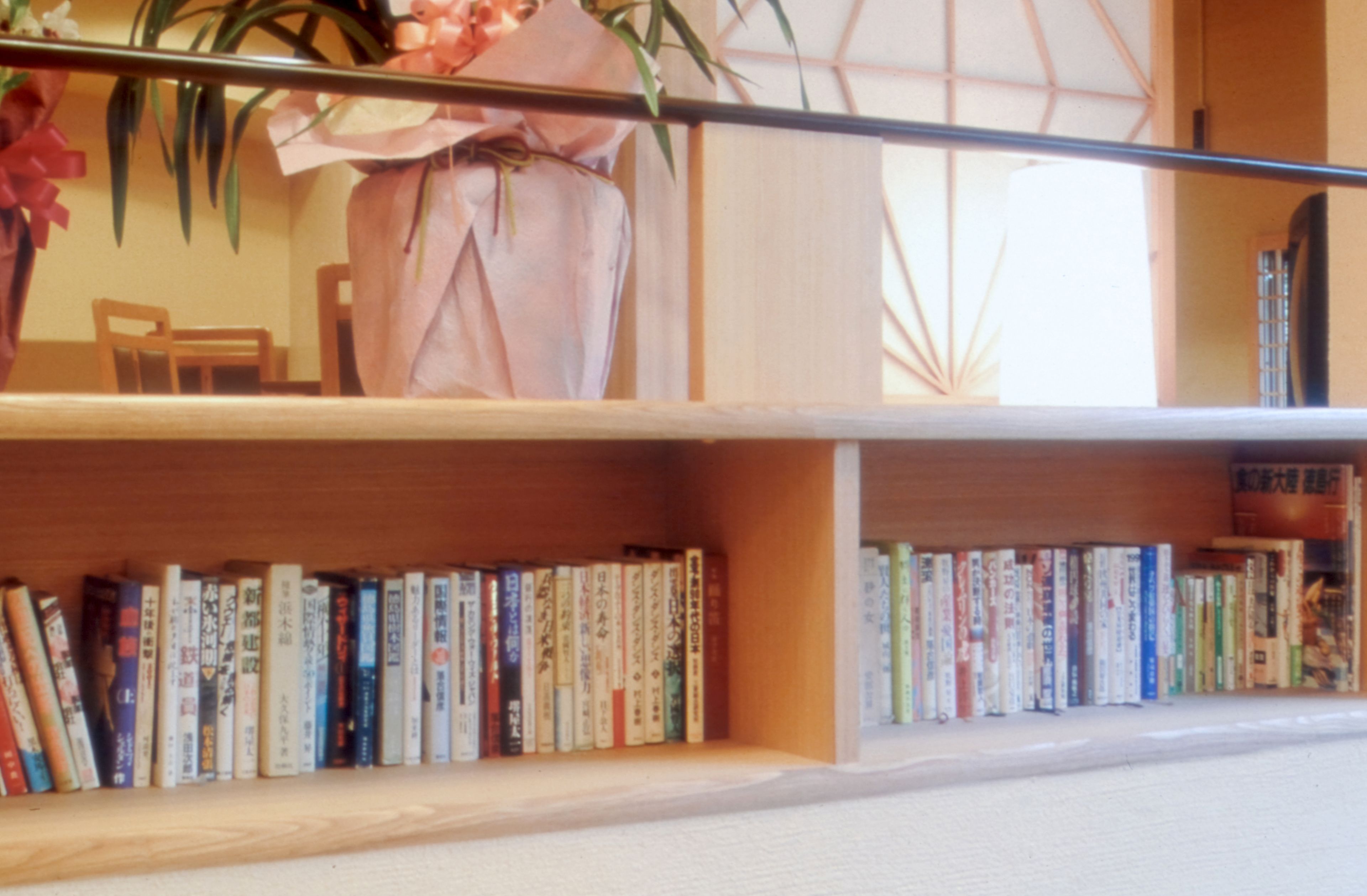Una libreria con libri e un vaso di fiori.