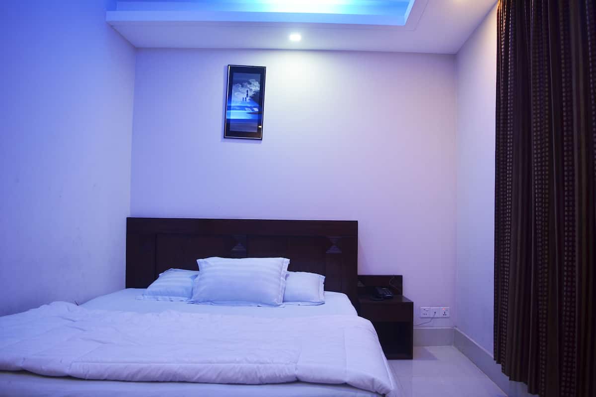 A bedroom with a bed, a nightstand, a wall-mounted picture, and a ceiling light.