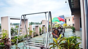 Une terrasse sur le toit avec une balançoire, des sièges d’extérieur et des plantes en pot.