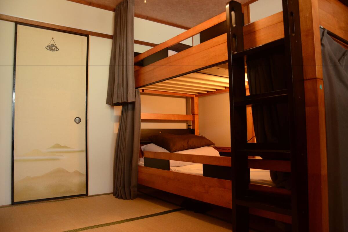 Habitación con literas, puerta corredera y cortina.