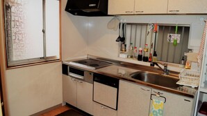 A compact kitchen with a stove, dishwasher, and sink. - Peace House Abeno - Hostel (Osaka)