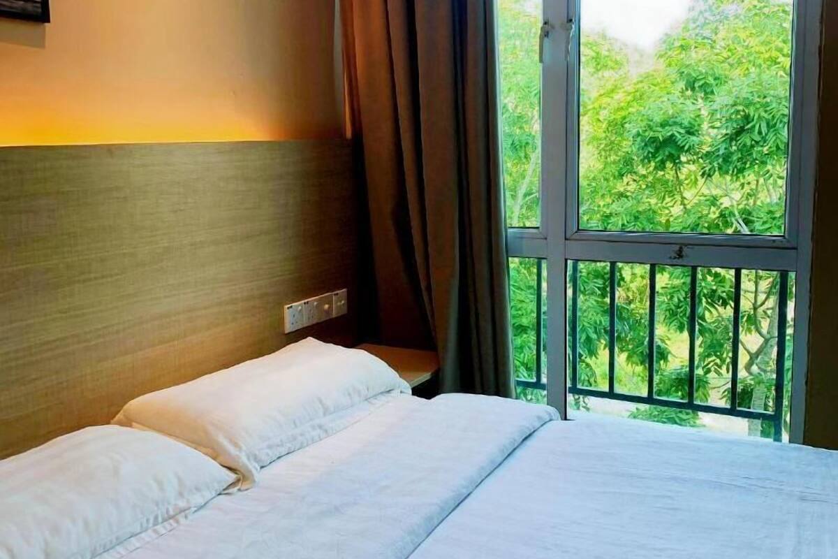 A hotel room with a bed, a window with curtains, and framed pictures on the wall.