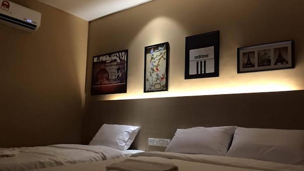 A hotel room with two beds, a wall-mounted air conditioner, and three framed pictures. - 91 Street Boutique Inn (Miri)