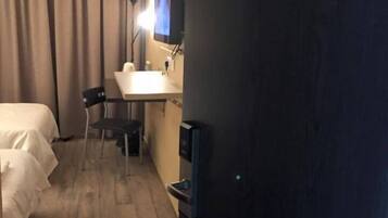 Une chambre d’hôtel équipée d’un lit, d’un bureau, d’une chaise, d’une télévision et d’une pancarte indiquant « Chambre 311 ».