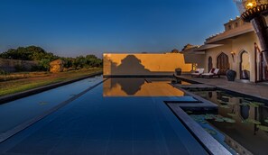 A serene pool area with a clear view of the surrounding landscape and a traditional building with arched windows.