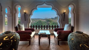A room with two sofas facing a view of a mountainous landscape, a small table, and decorative vases.