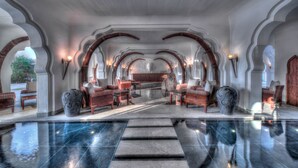 A spacious lobby with a reflective floor, arched ceilings, and seating areas.