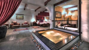 A spa room with a large bathtub, a sofa, and a bed.