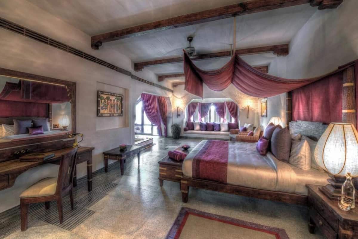 A bedroom with a large bed, a desk, and a chair.