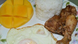 A plate with a fried egg, grilled chicken, and mango slices served with white rice. - Bluewaves Beach House (Boracay Island)