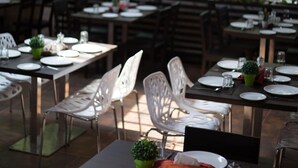 An outdoor dining area with tables and chairs, surrounded by trees. - HM Suites & Studios Bangalore (Bengaluru)