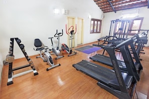 Ein Fitnessstudio mit verschiedenen Trainingsgeräten, darunter Laufbänder, ein Crosstrainer und ein Ergometer.