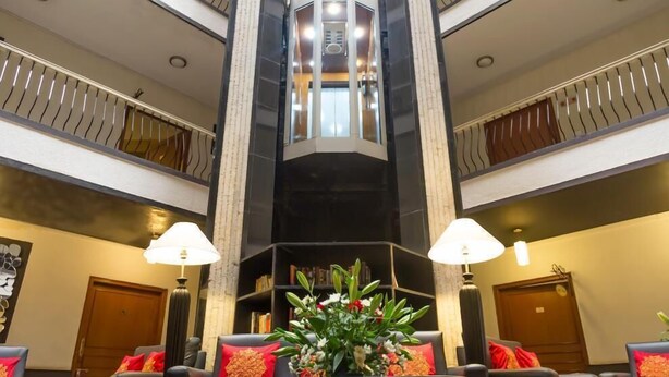 A hotel lobby with a central staircase, multiple floors, and a seating area with a table and chairs. - HM Suites & Studios Bangalore (Bengaluru)