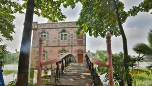 Un bâtiment en pierre doté de fenêtres en arc de cercle et d’un pont en bois avec des garde-corps en fer qui y mène.