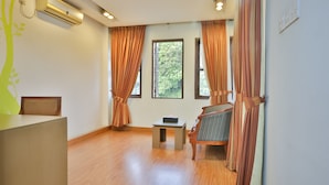 Une pièce avec un plancher en bois, une petite table sur laquelle se trouve une boîte, une chaise et un bureau avec une autre chaise.