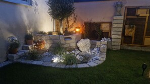 A landscaped garden with a stone wall, potted plants, and a statue. - ApartmentHotel Vollumen (Redwitz an der Rodach)