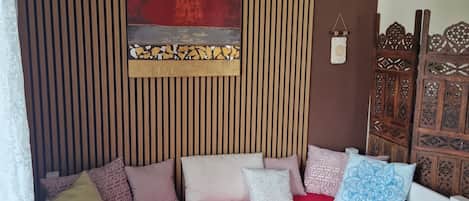 A room with a white sofa bed, a red throw blanket, and a wall with vertical wooden slats.