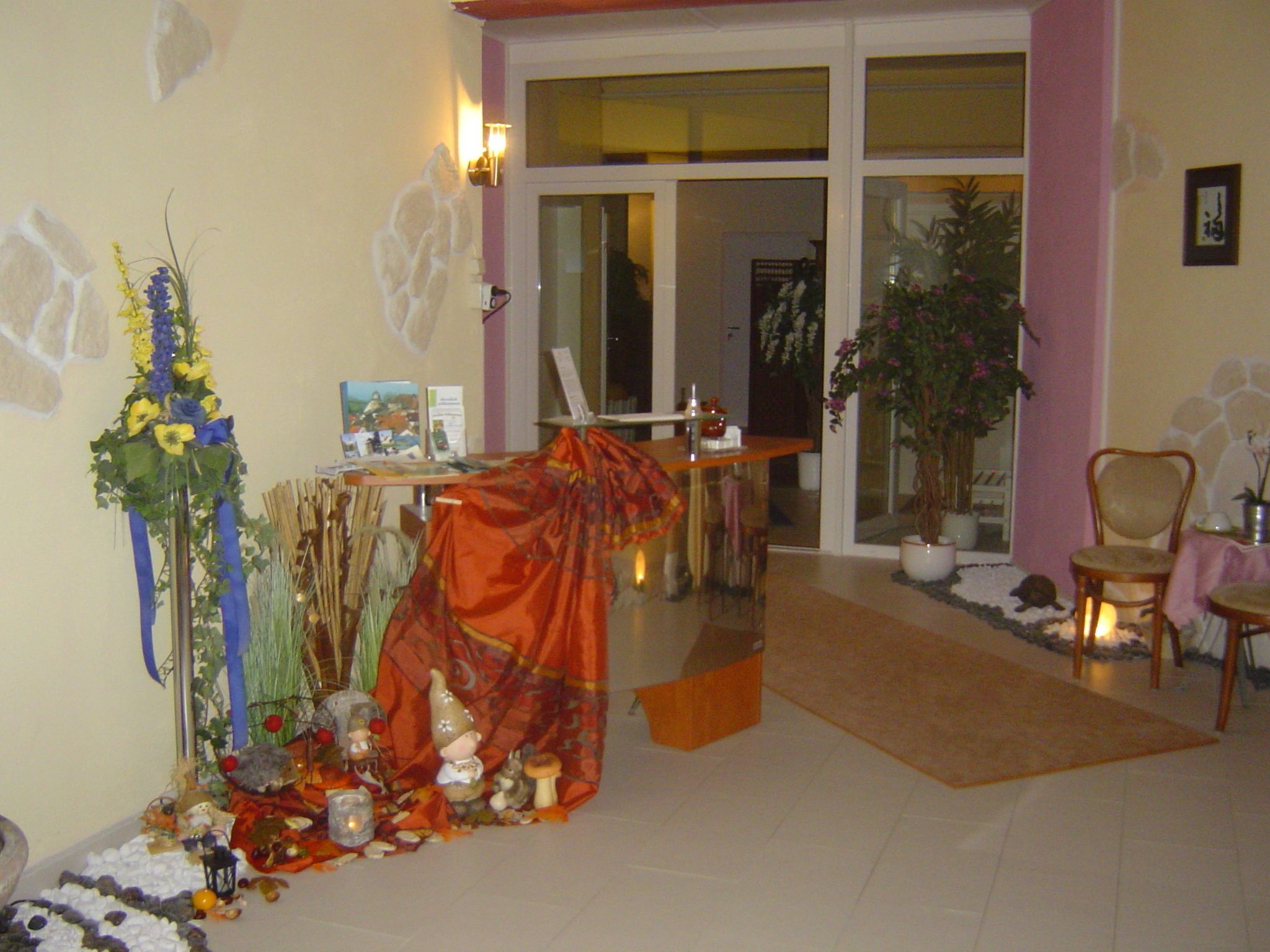 A room with a dining area, a large window, and a potted plant.
