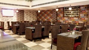 Restaurante com móveis de vime, piso xadrez e parede decorada com placas de carro.