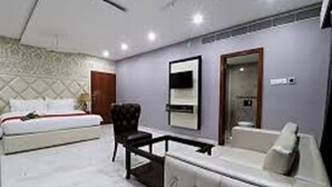 Quarto de hotel moderno com cama, sofá, poltrona e escrivaninha.