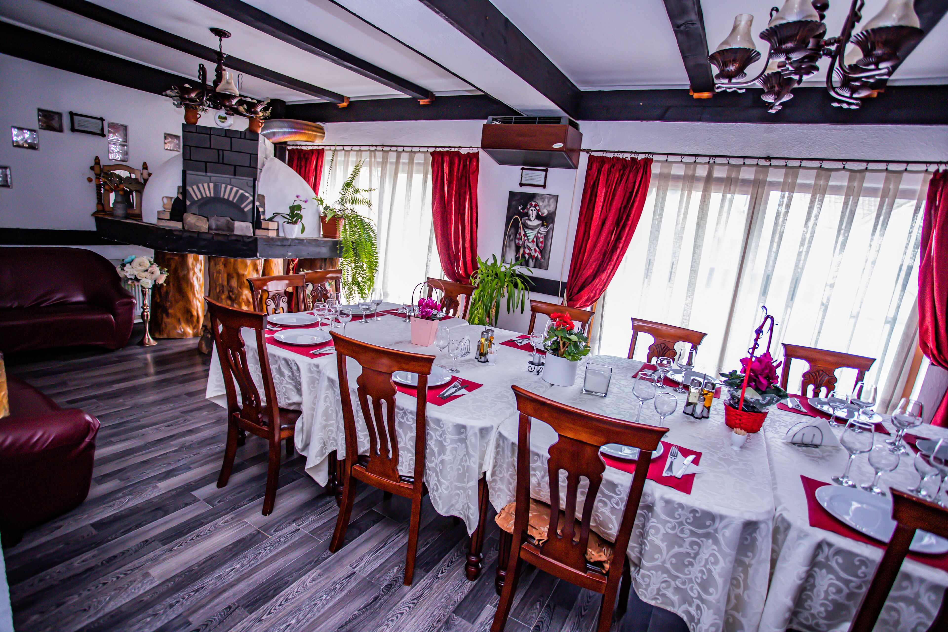 A dining area with multiple tables set for a meal, wooden chairs, and a fireplace.