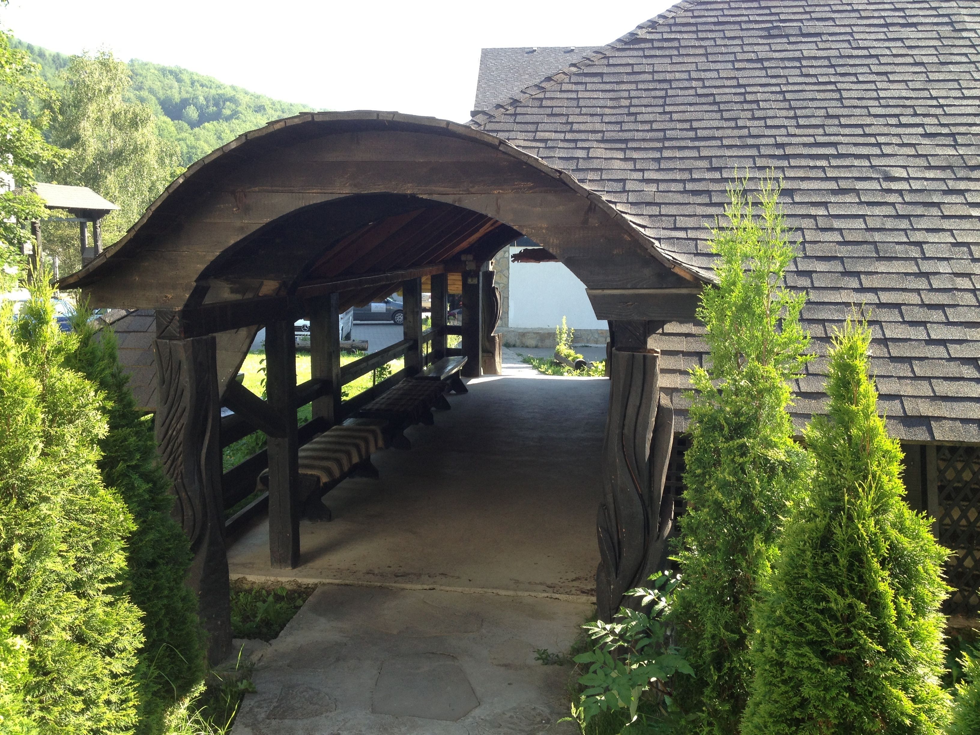 A covered wooden walkway leading to a building with a stone roof.
