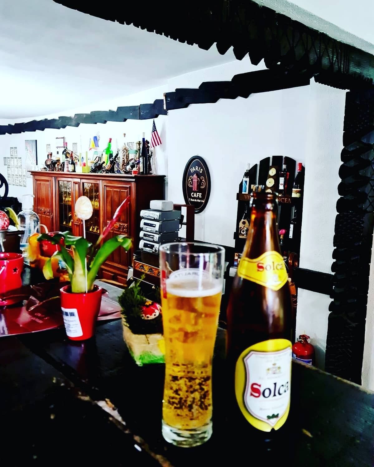 A bar area with a glass of beer, a Solcasa bottle, and a vintage jukebox.