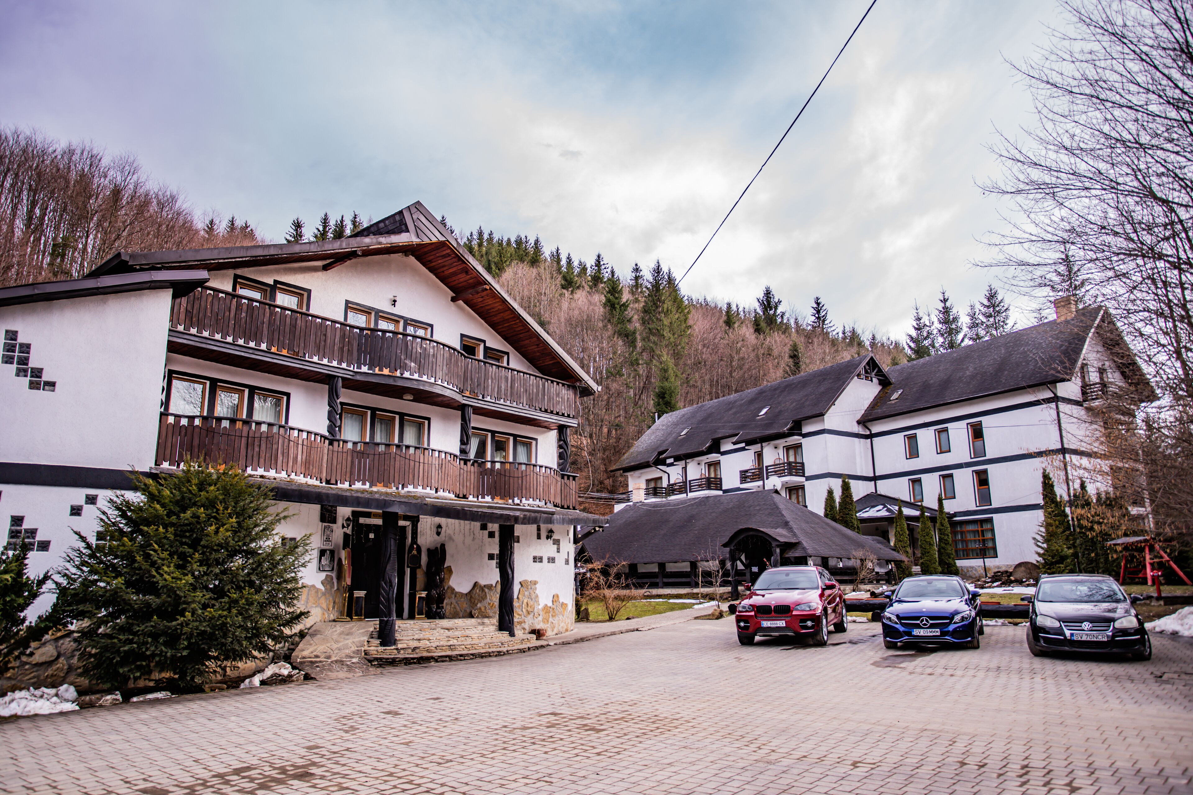 A building with a balcony, a driveway, and parked cars.